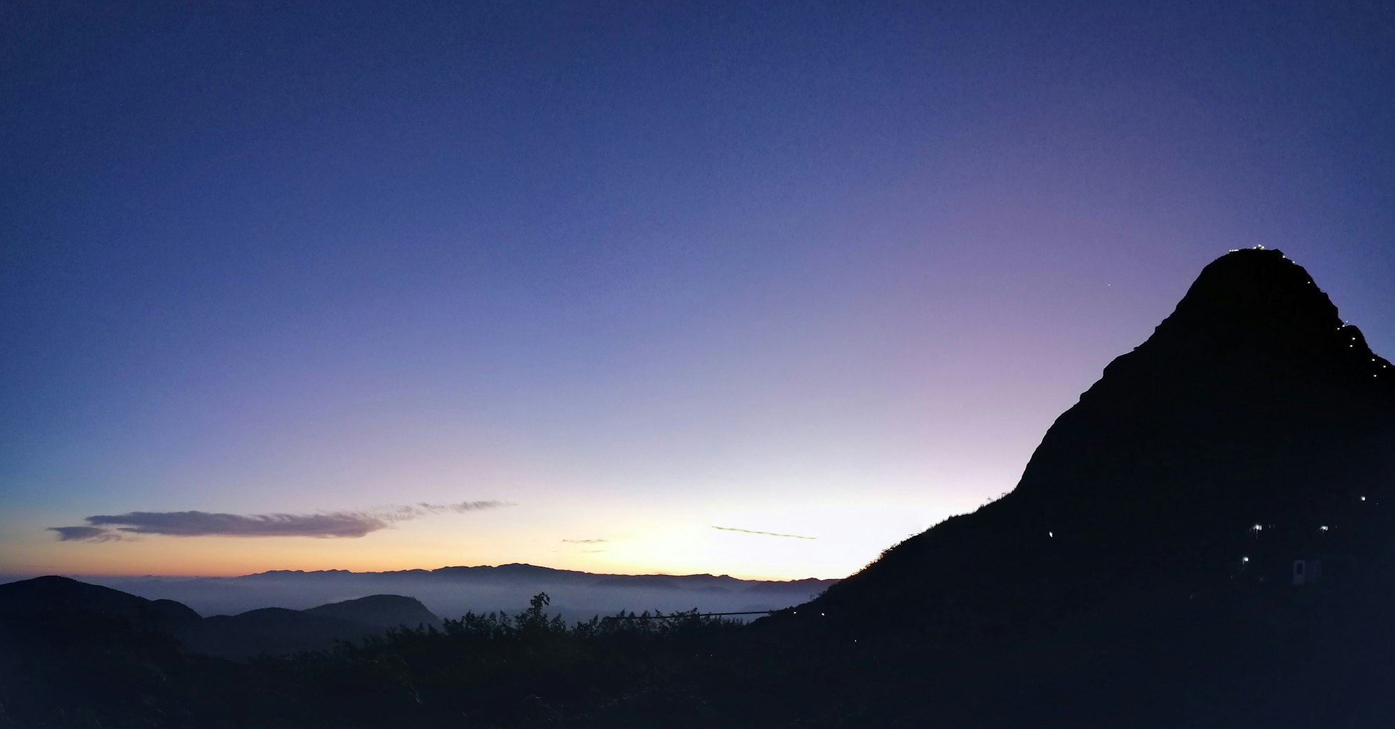 A conical peak rising above cloud at dawn