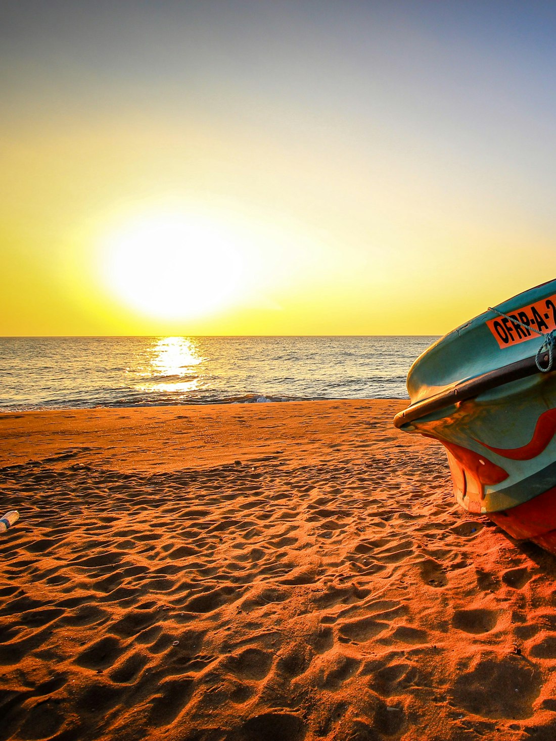 A painted fishing boat pulled up on the sand at Negombo at sunset